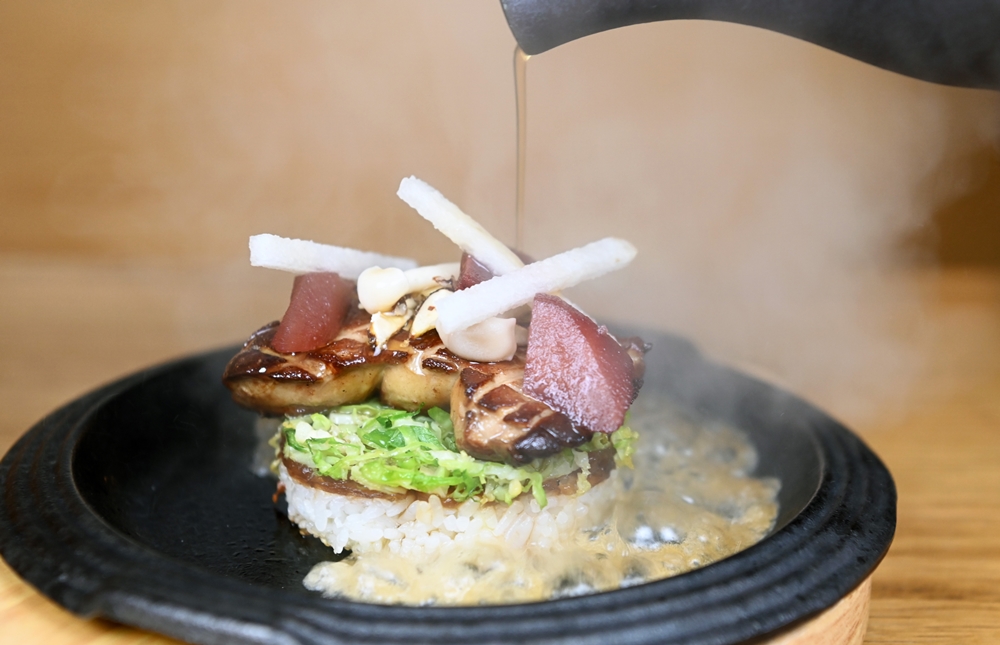 뜨거운 철판에 누룽지를 만들고 그 위에 양파, 푸아그라와 배 등이 올려진 누룽지 푸아그라